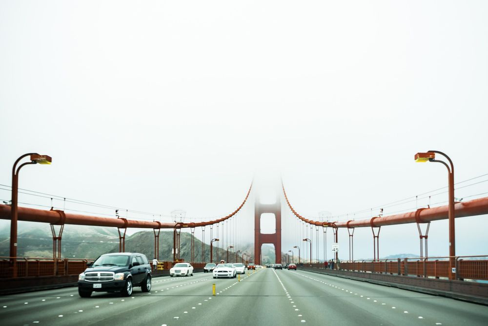 Scenic fog rolling over the iconic Golden Gate Bridge in San Francisco with rusty red towers visible through the mist.