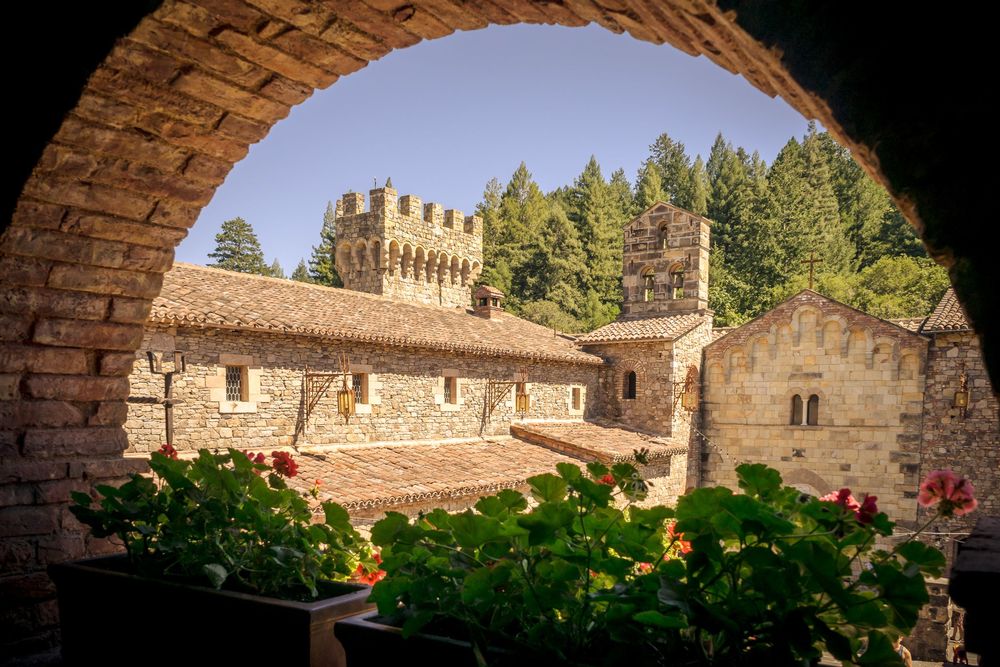 Historic monastery ruins with stone archways and walls set against a scenic forest landscape.