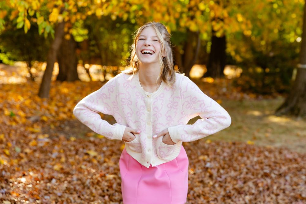 An outdoor autumn photoshoot in a park with vibrant yellow fall foliage.