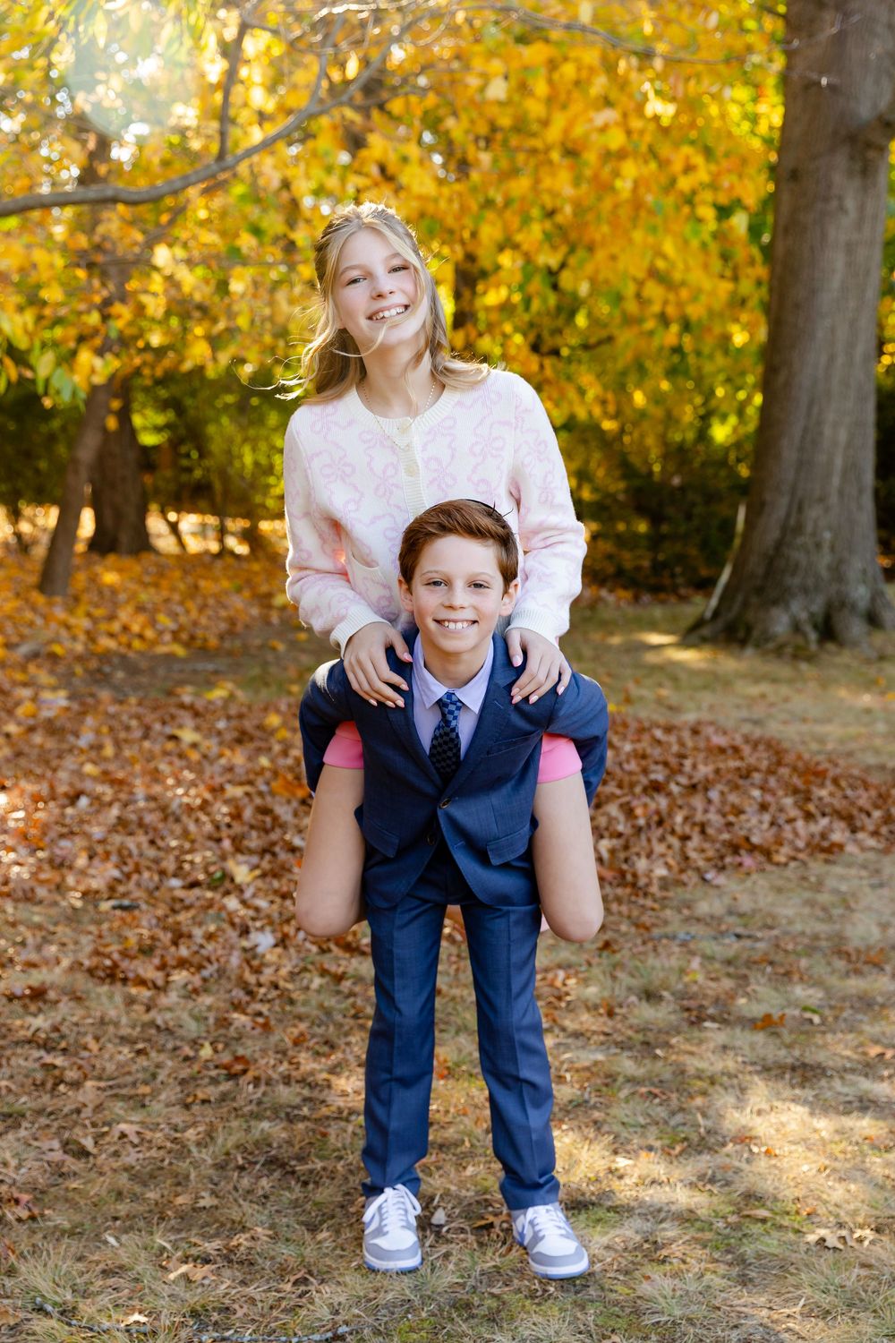 Two people playing and laughing together in a park filled with golden autumn leaves.