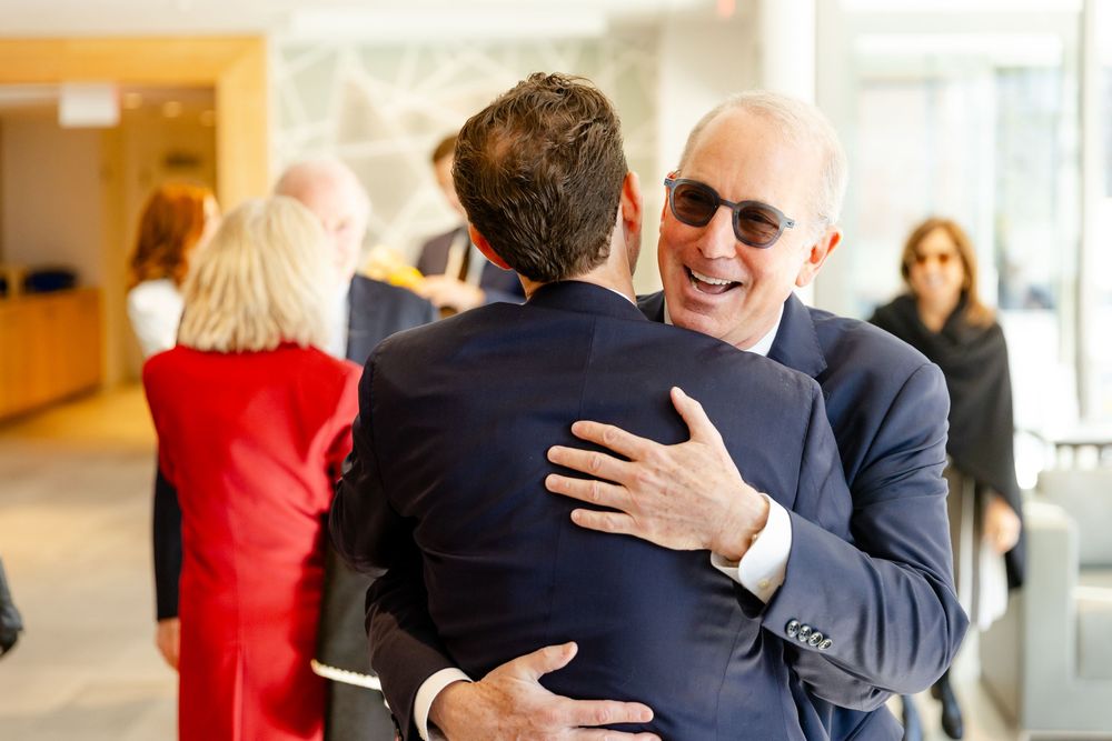 Several guests sharing warm embraces at an indoor celebration event.