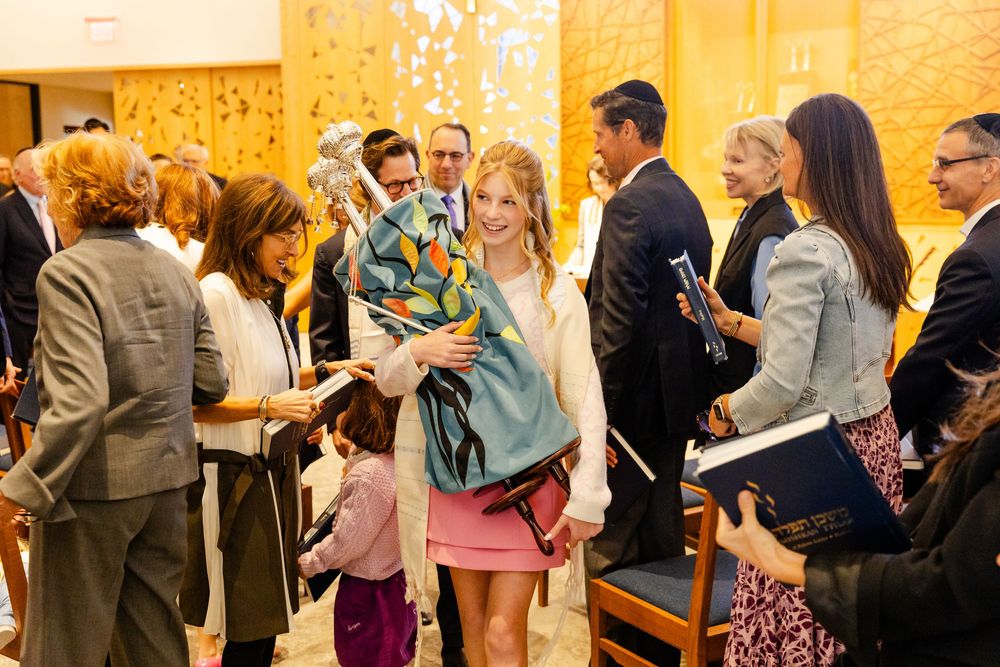 Large group of people gathered at a formal event in a gold-toned room.