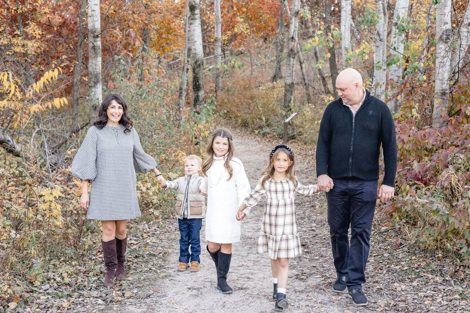 Family walking together through a wooded area with fall foliage in the background.