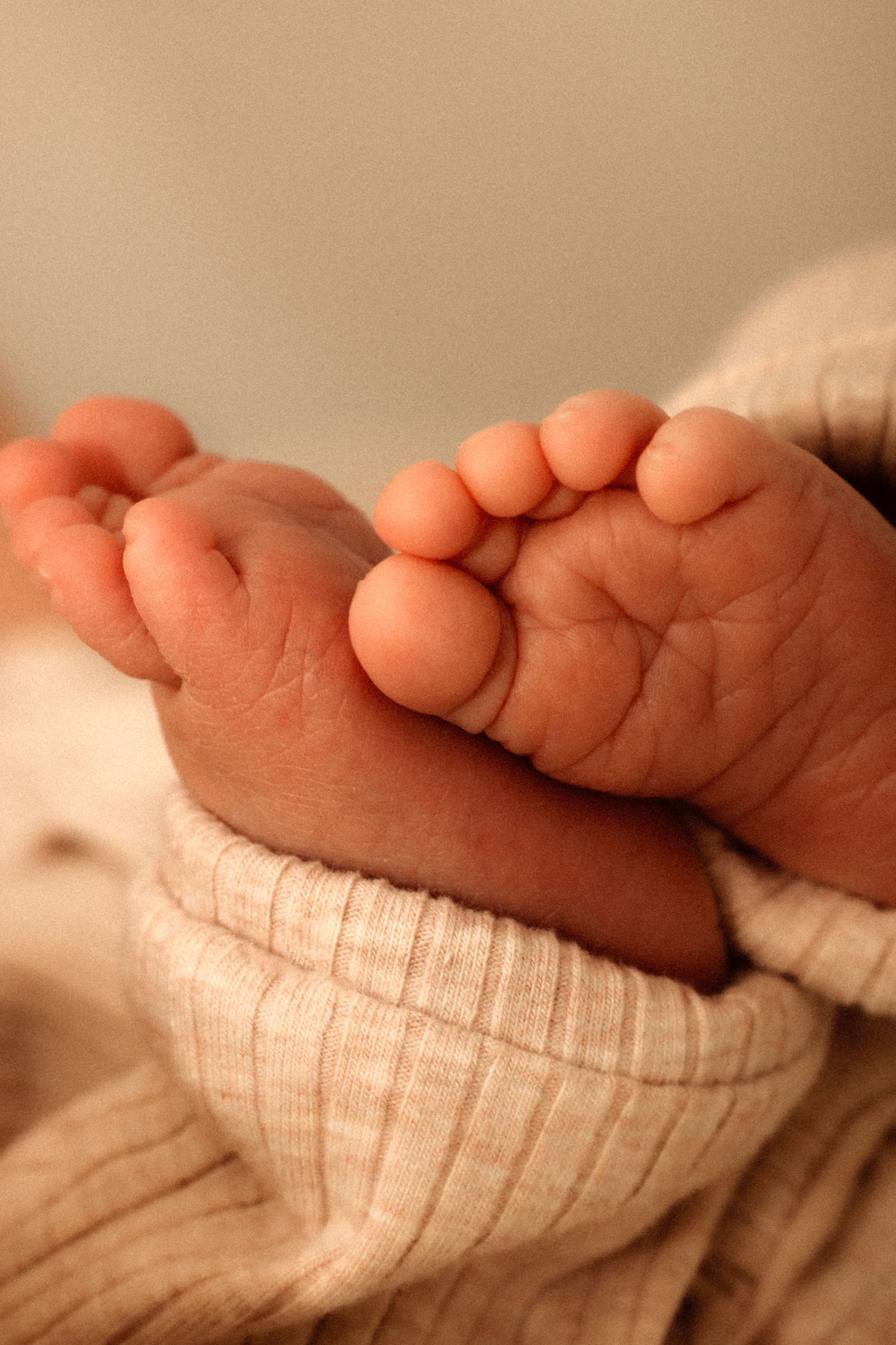 Close-up of tiny baby feet wrapped in cozy white knit fabric showing delicate toes and soft skin. Denia newborn photographer
