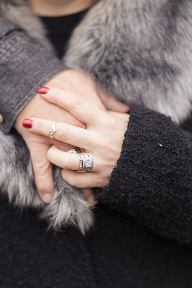 Close-up of hands with engagement and wedding rings against fur coat.