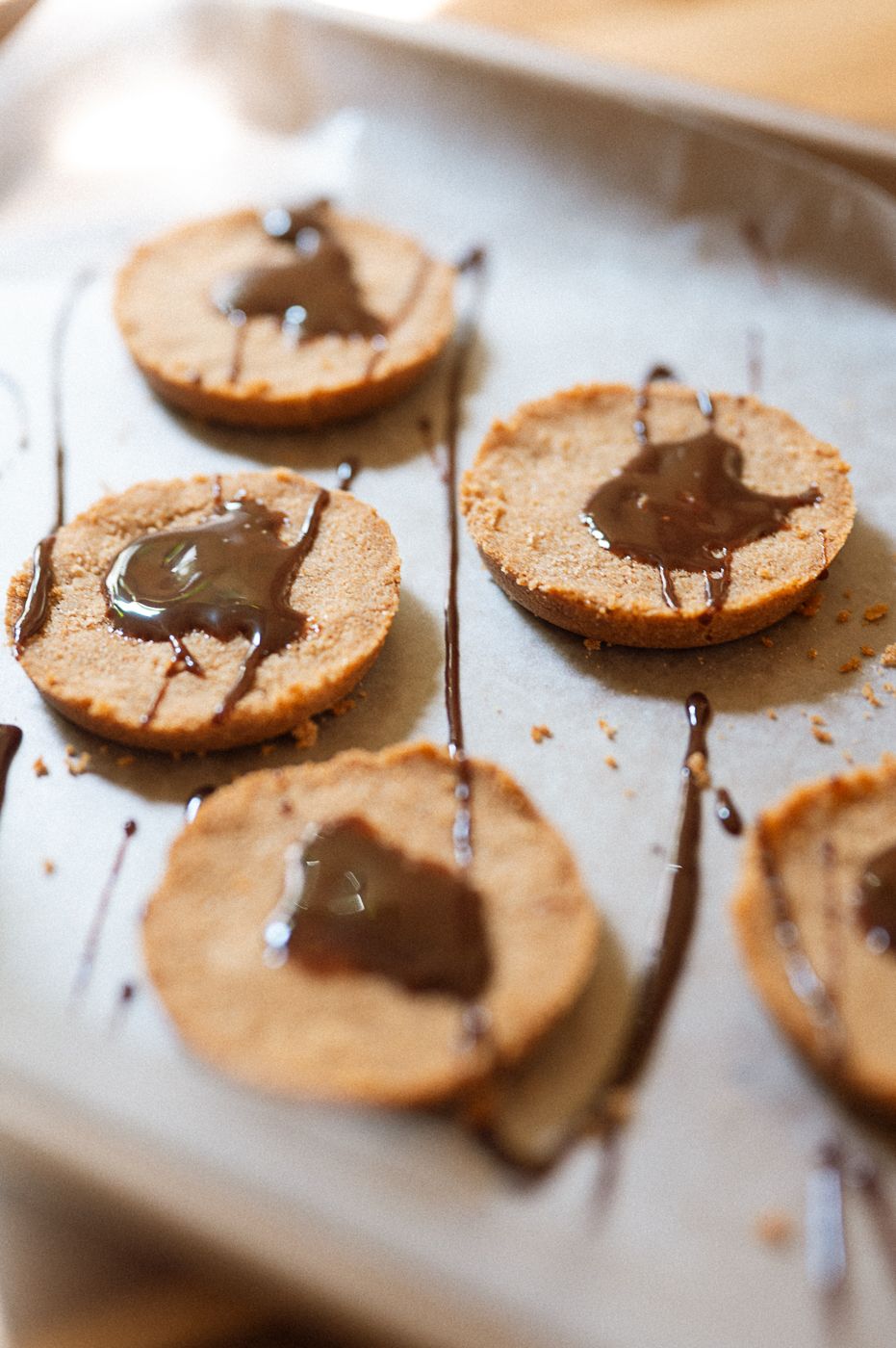 Close-up macro shot of homemade chocolate-filled sandwich cookies arranged in a row on a light surface.