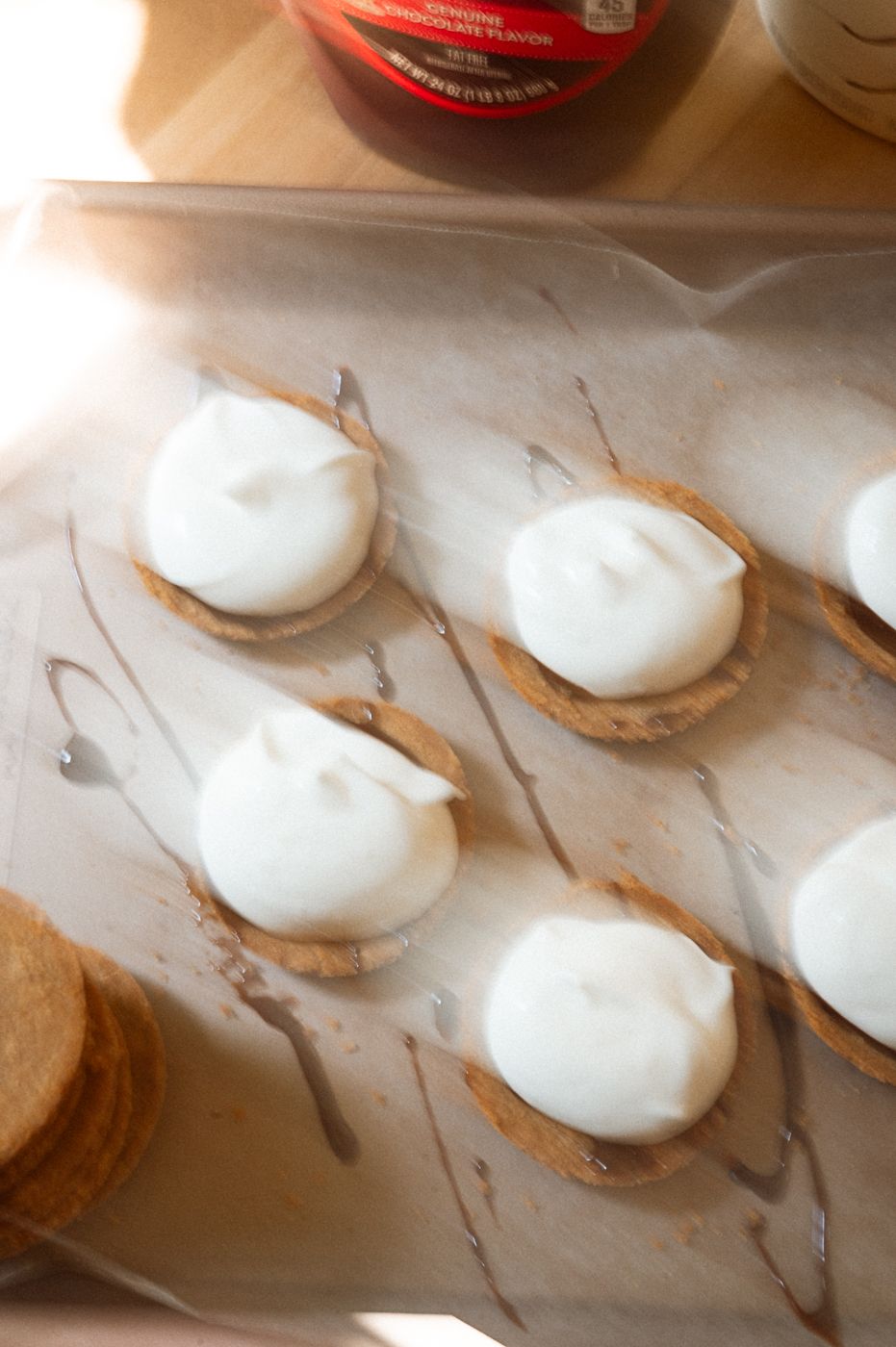 Row of perfectly piped white meringue dollops on a white marble surface waiting to be baked.
