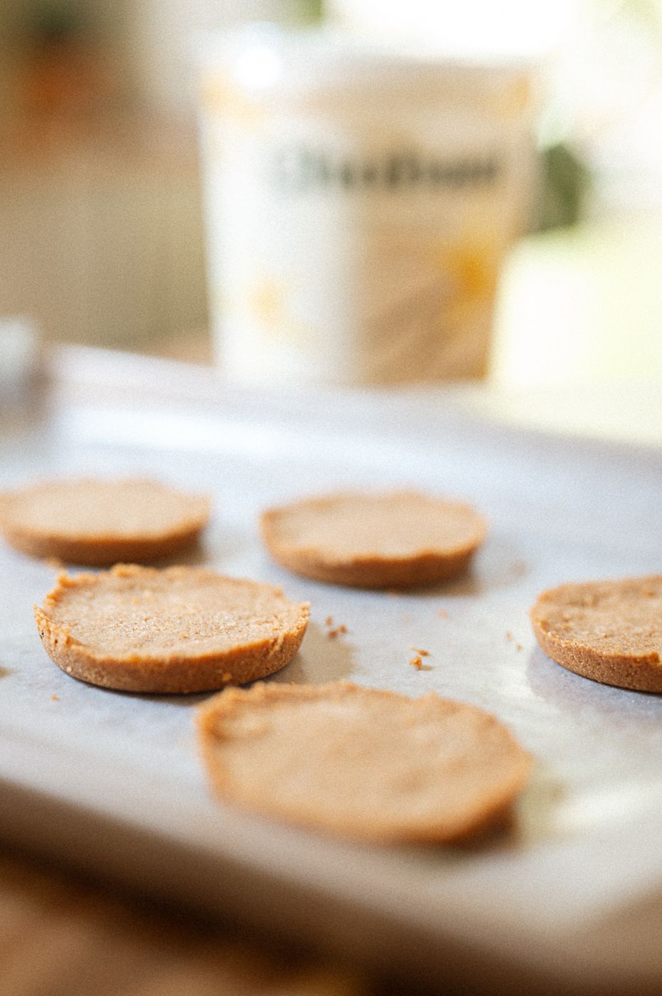 Freshly baked golden brown cookies arranged in a row on a white baking sheet with shallow depth of field.