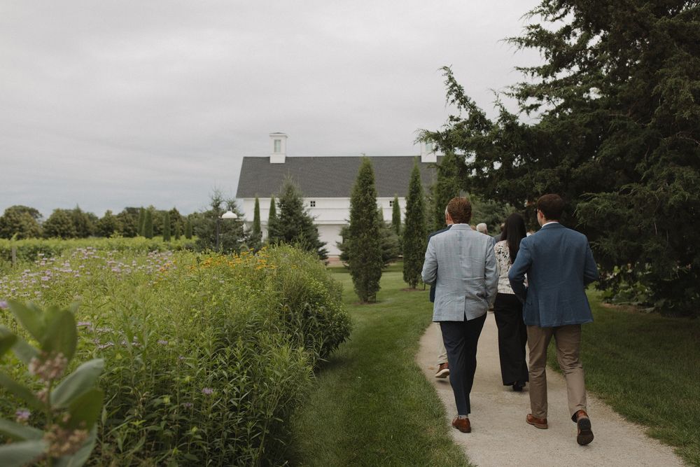 People walking down garden path towards white church building.