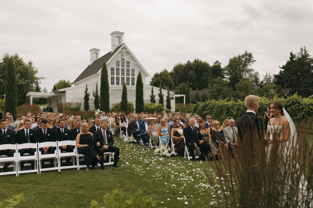 Wide view of wedding ceremony site with white chairs and chapel building in background.