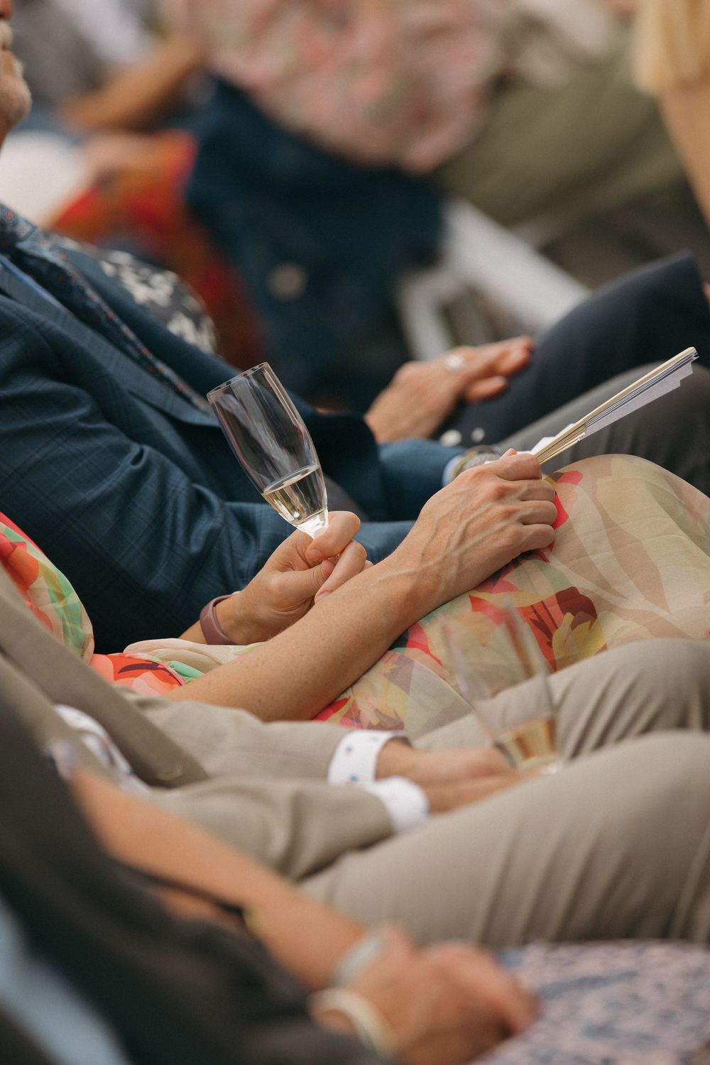 Wedding guests hold ceremony programs while seated in rows.