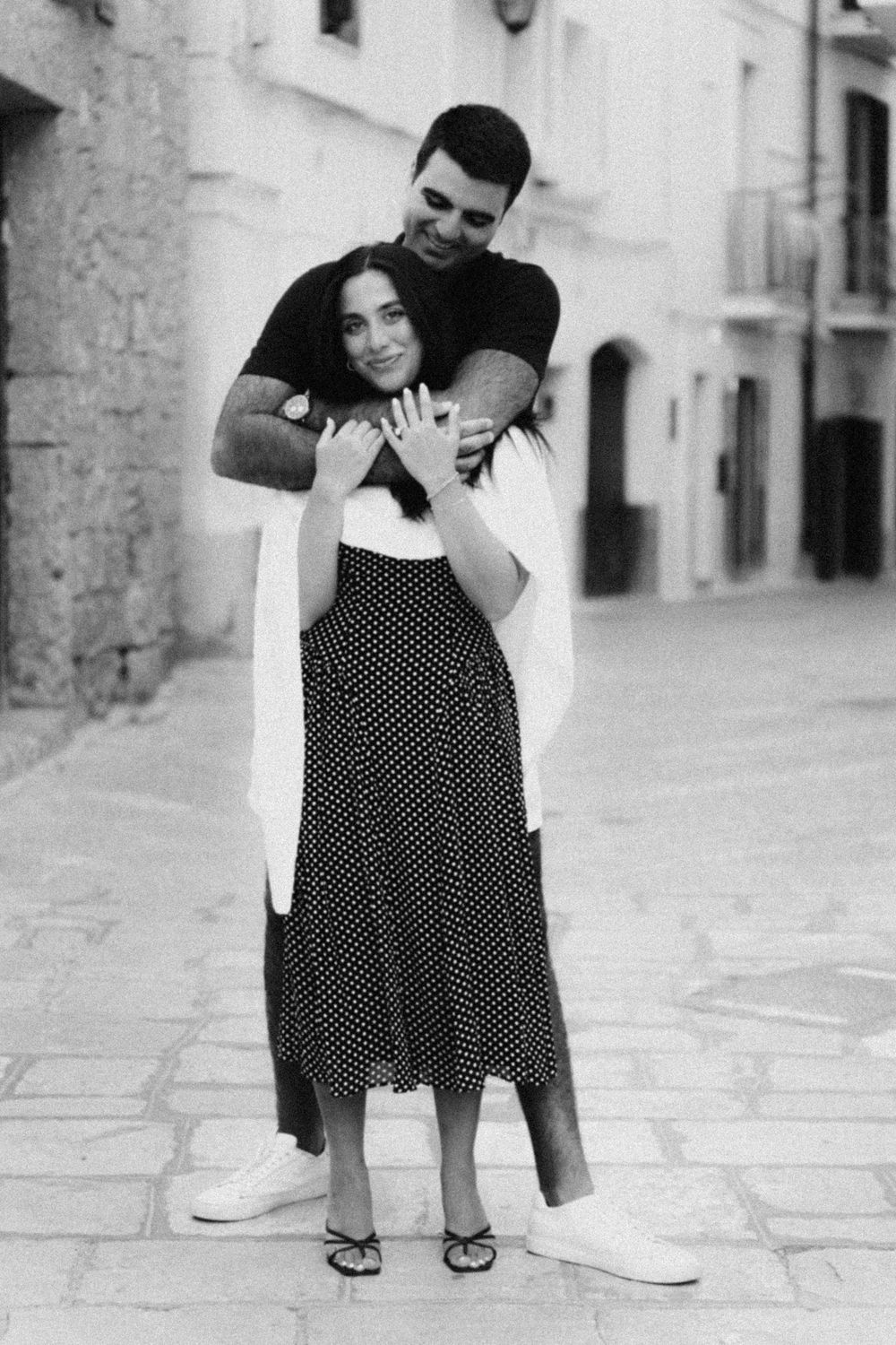 A romantic black and white photo sequence showing a couple playfully interacting in a European street setting.