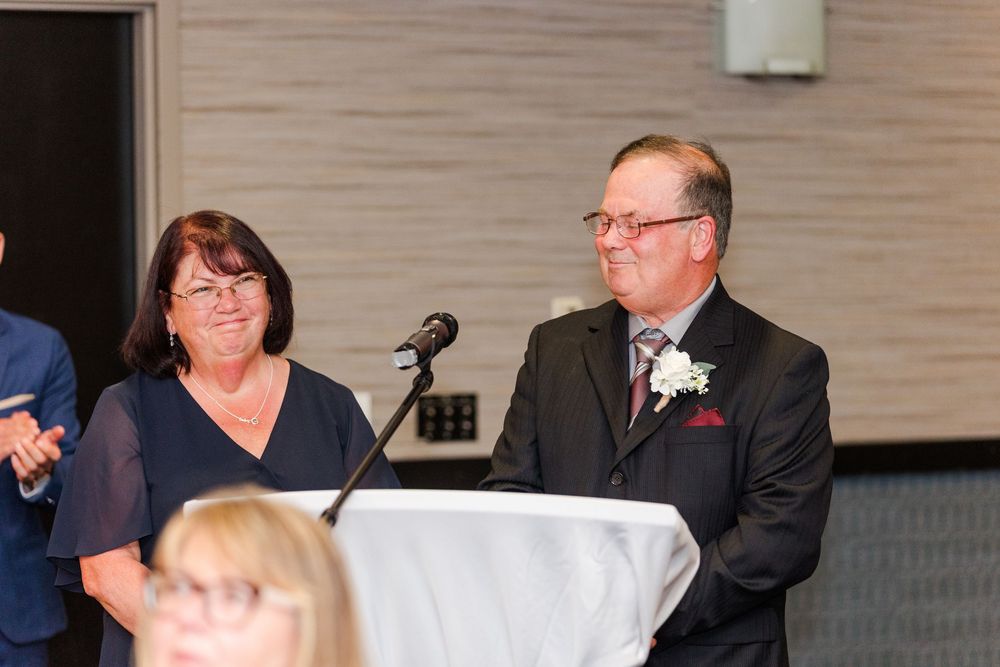 People seated at elegant tables smile and laugh during what appears to be a formal wedding reception or banquet.