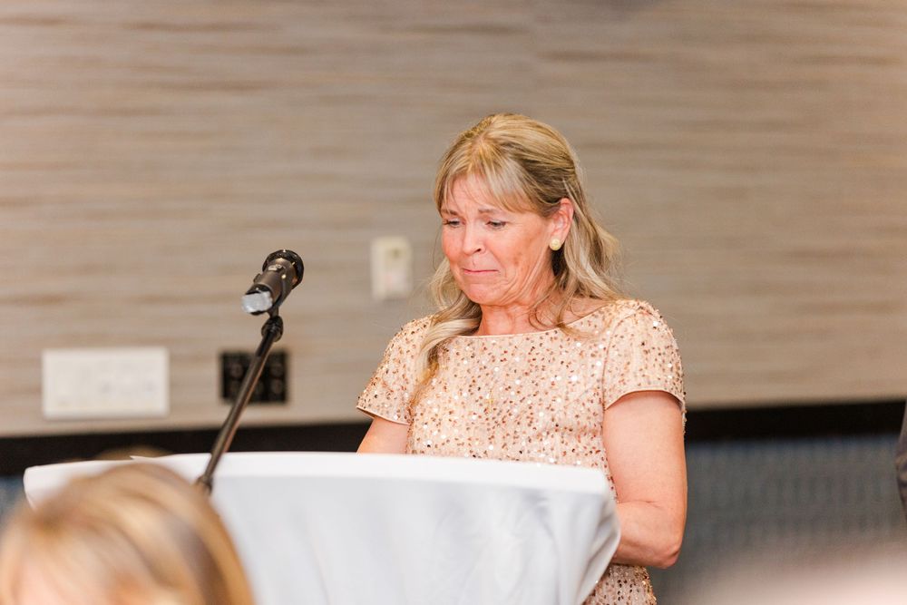 Person in peach-colored dress seated at event table during formal gathering.