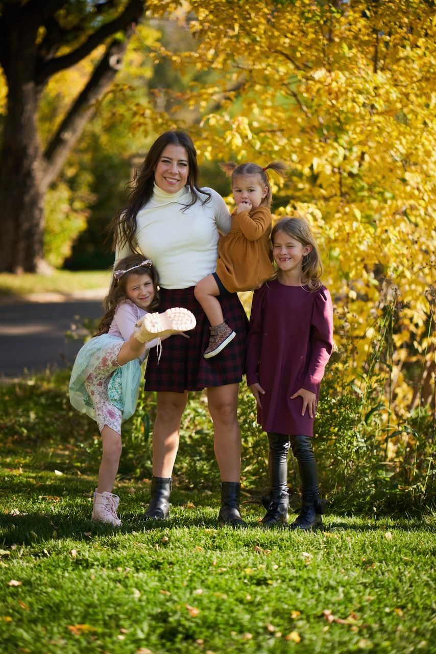 A parent and children enjoy a fall day outdoors with golden leaves in the background photographed by Evan Will in Calgary, Alberta