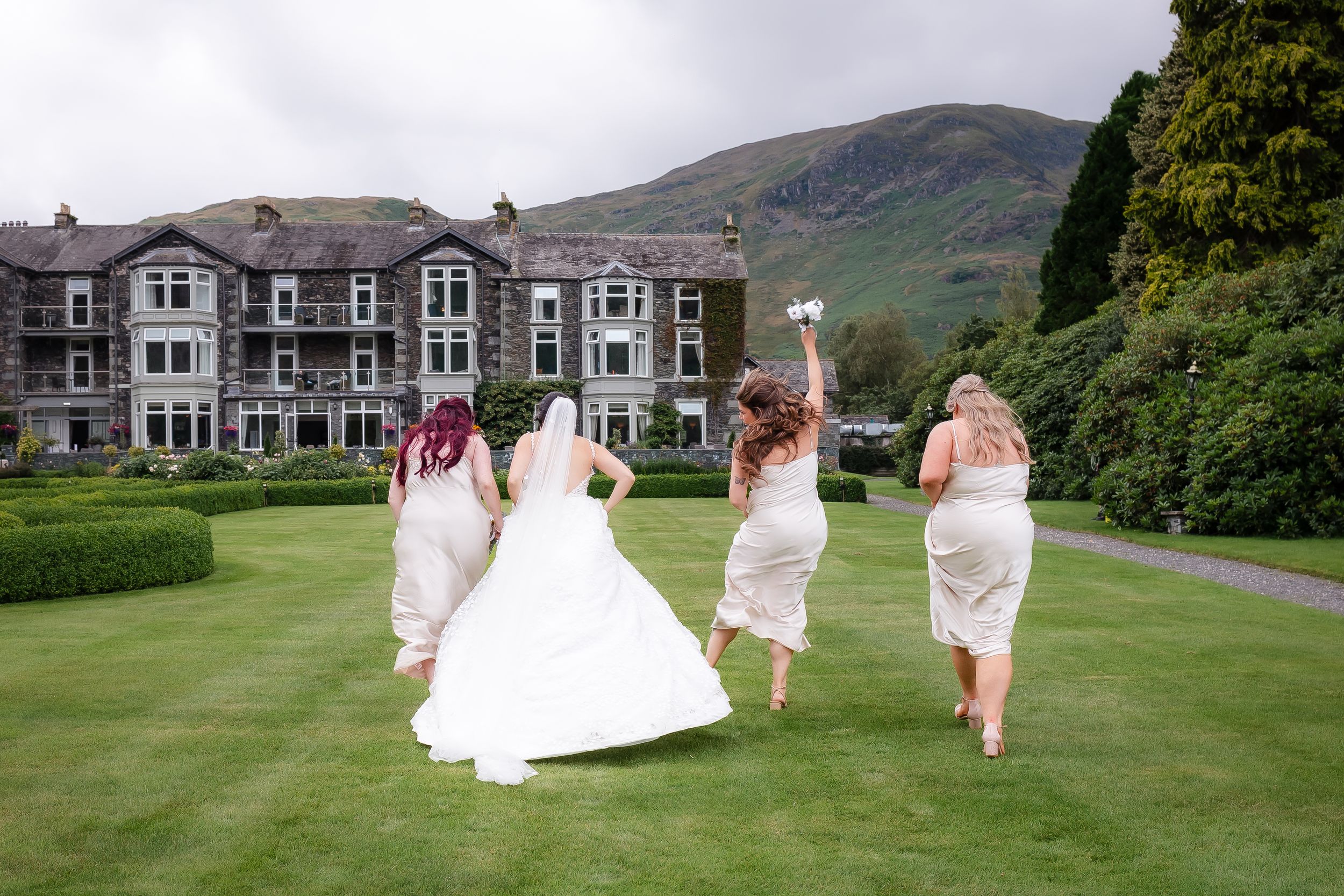 wedding photography in Cumbria - bridesmaid fun running through the grounds