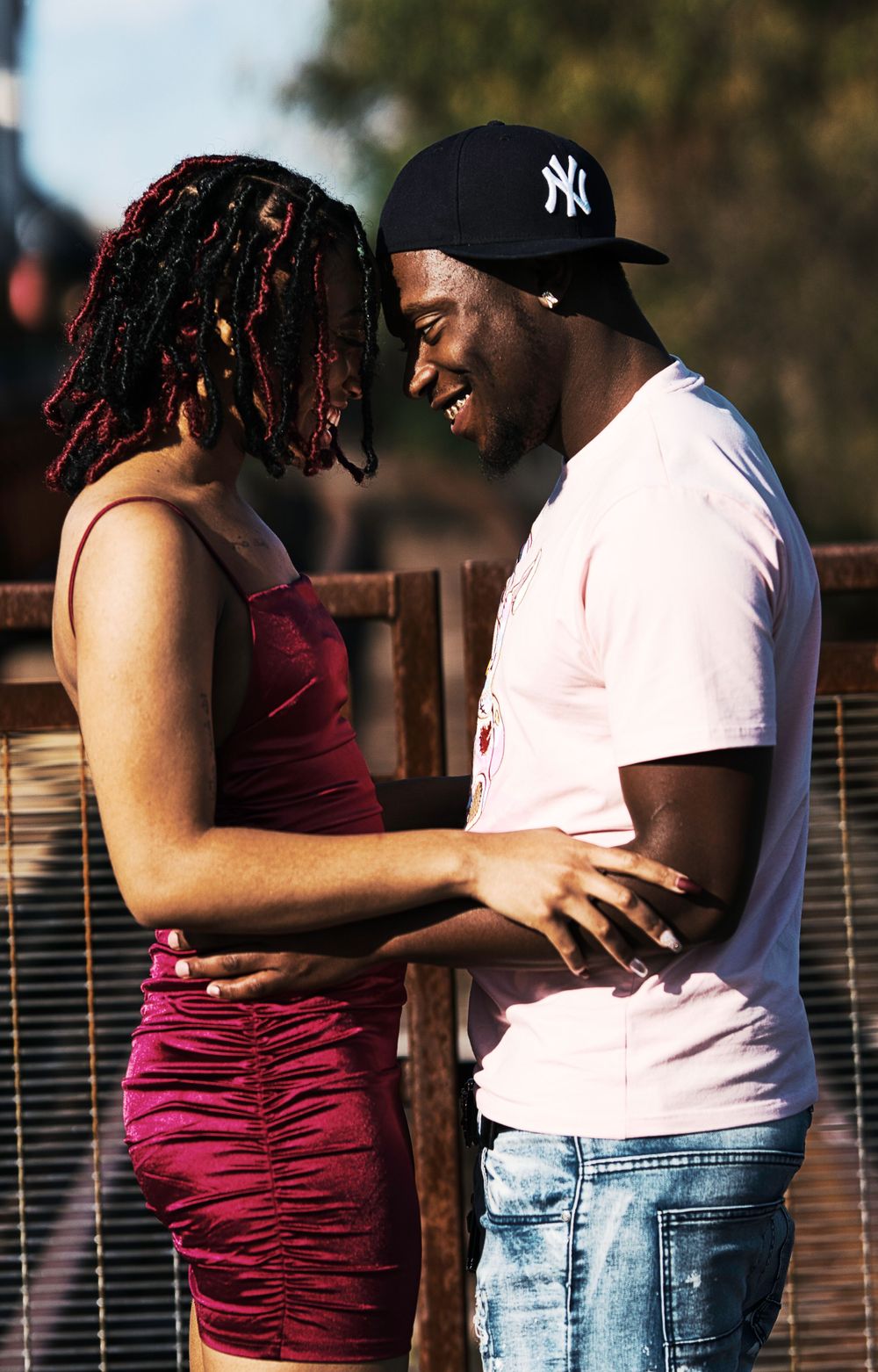 Romantic couple in casual attire sharing intimate moment on outdoor deck during sunset.
