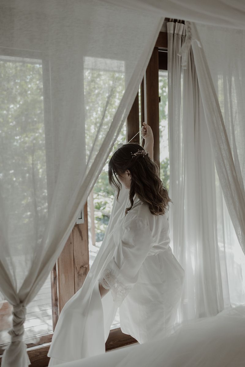 Bride in silk gown by window light during intimate elopement at La Valise Tulum Riviera Maya wedding photographer.