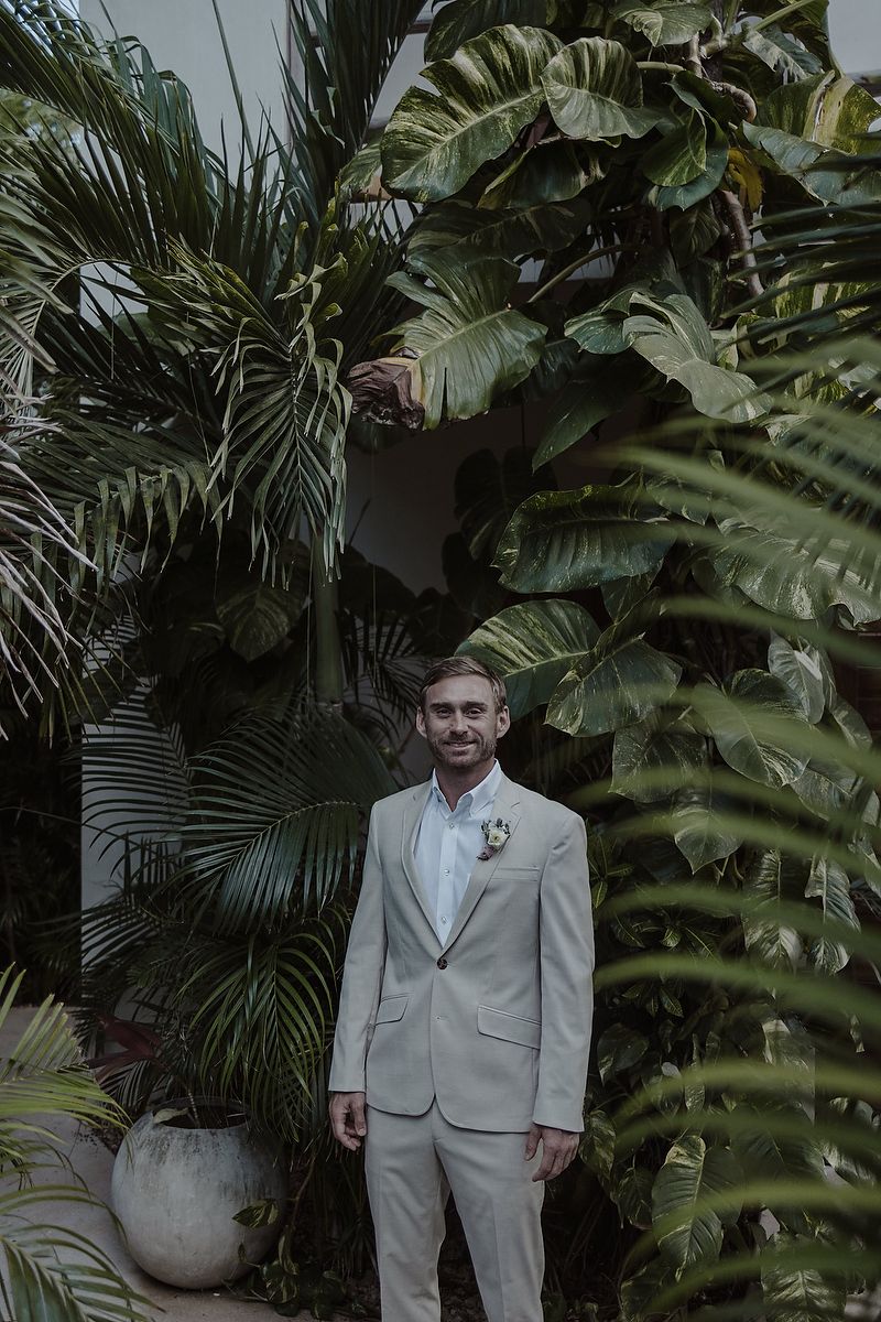 Groom standing among palm leaves during La Valise Tulum elopement Riviera Maya destination wedding photographer.