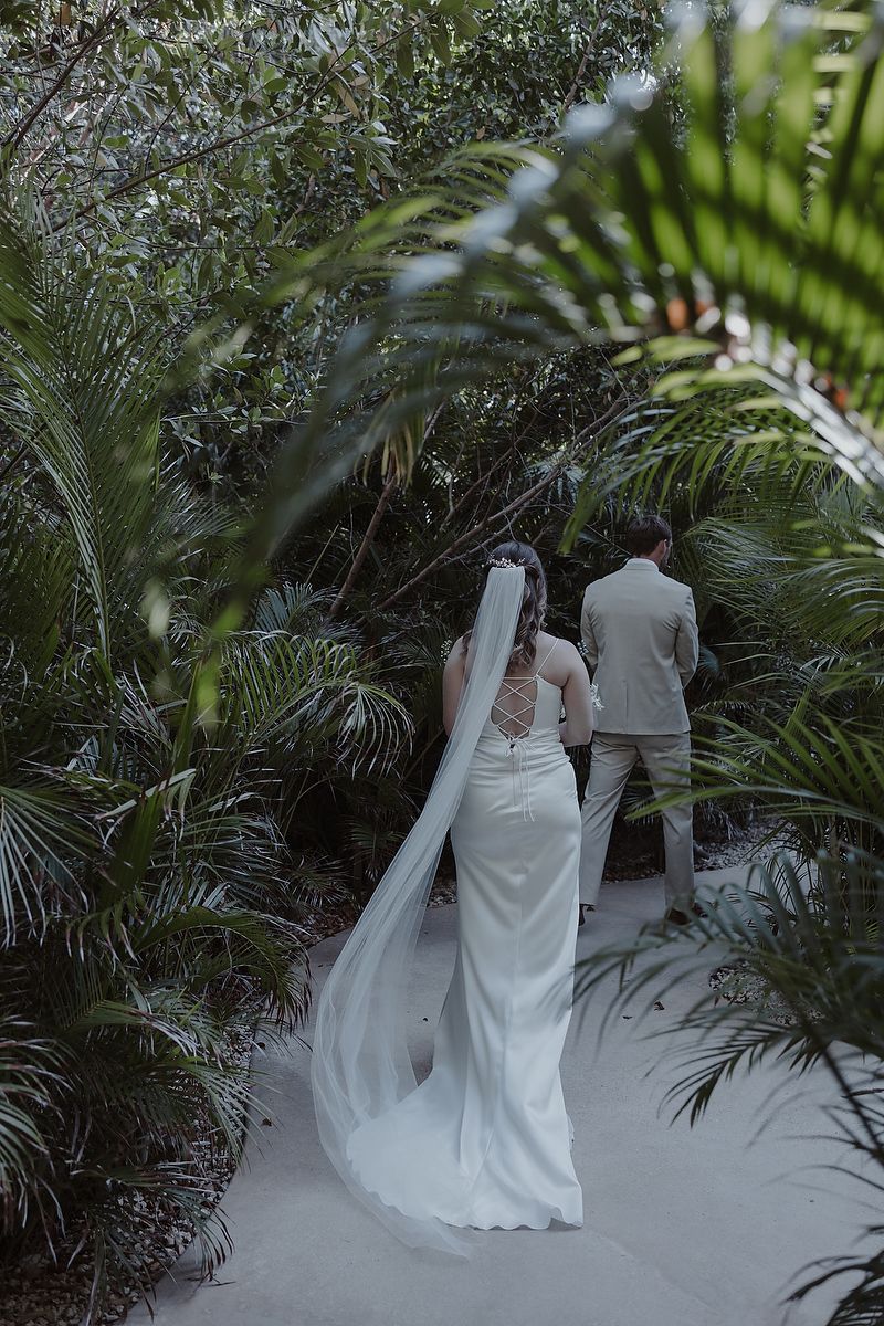 Artistic shot through leaves of bride in gown at La Valise Tulum elopement Riviera Maya wedding photographer.