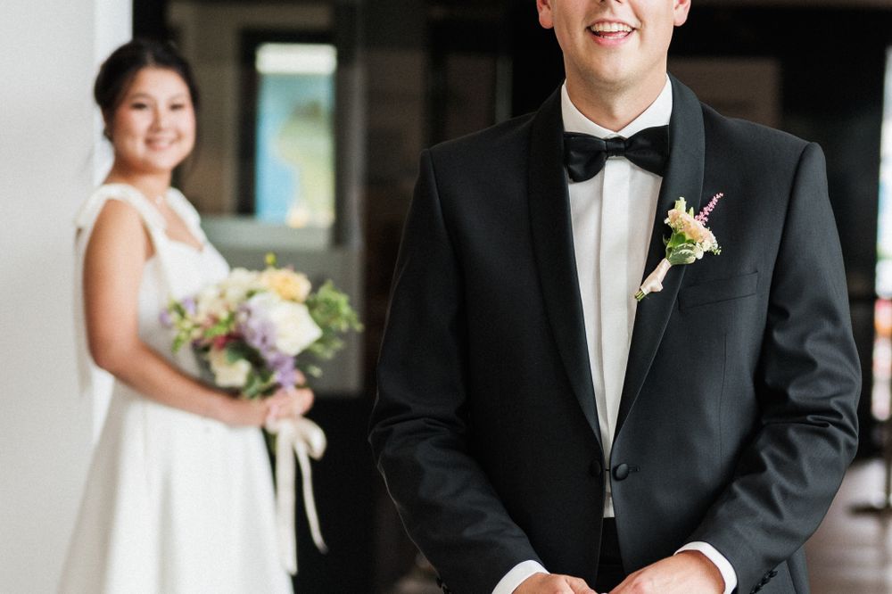 Wedding couple in classic formal attire with black tuxedo and white gown photographed indoors.