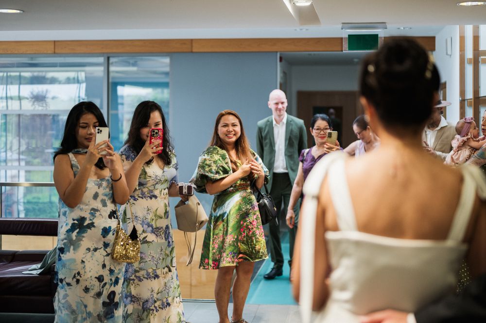 Wedding guests react with excitement as they see the bride in a bright modern space.