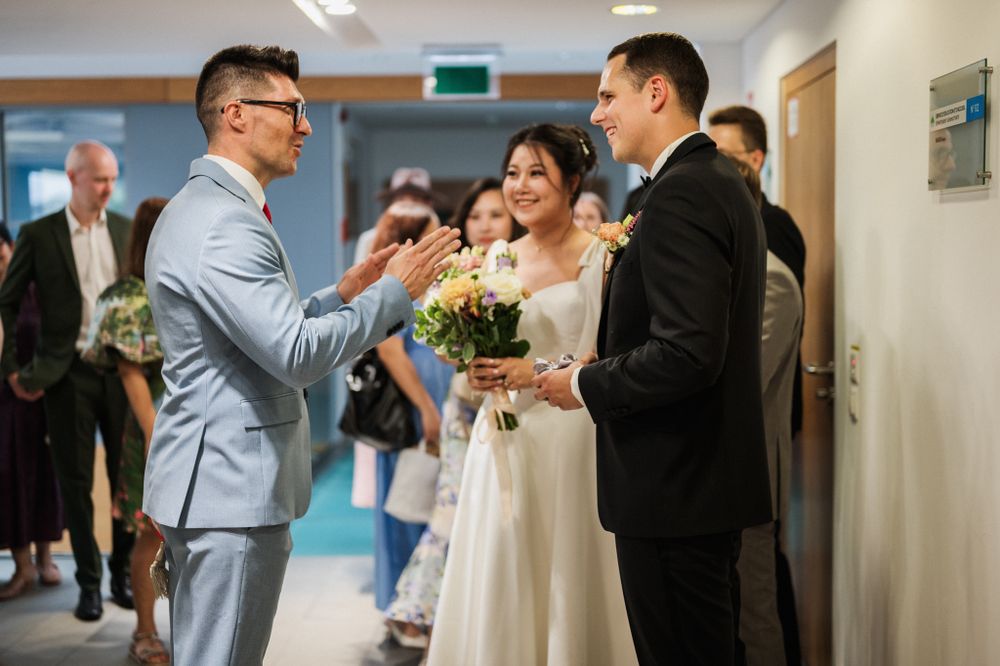 Wedding celebration scene in a hallway with guests in formal attire sharing a joyful moment.