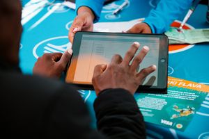 A close up image of a man completing forms on a tablet at an FNB activation campaign held in Soweto South Africa,