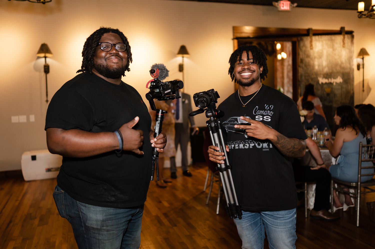 Two videographers with professional camera equipment working at an indoor event.