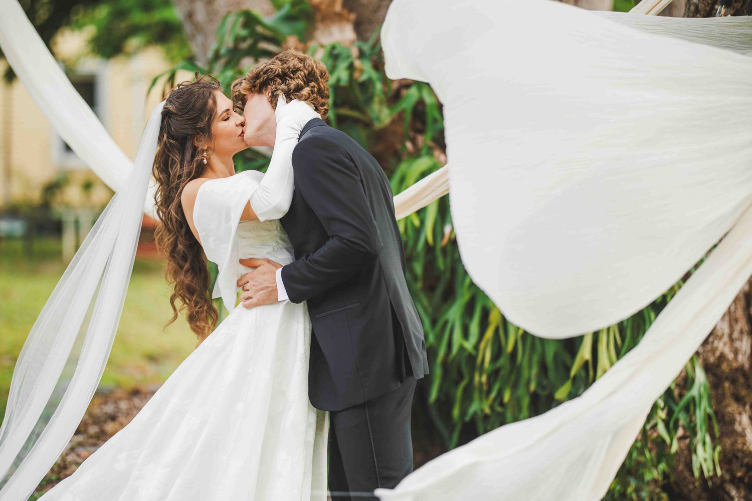 Wedding couple sharing an intimate moment as white fabric flows in the breeze.