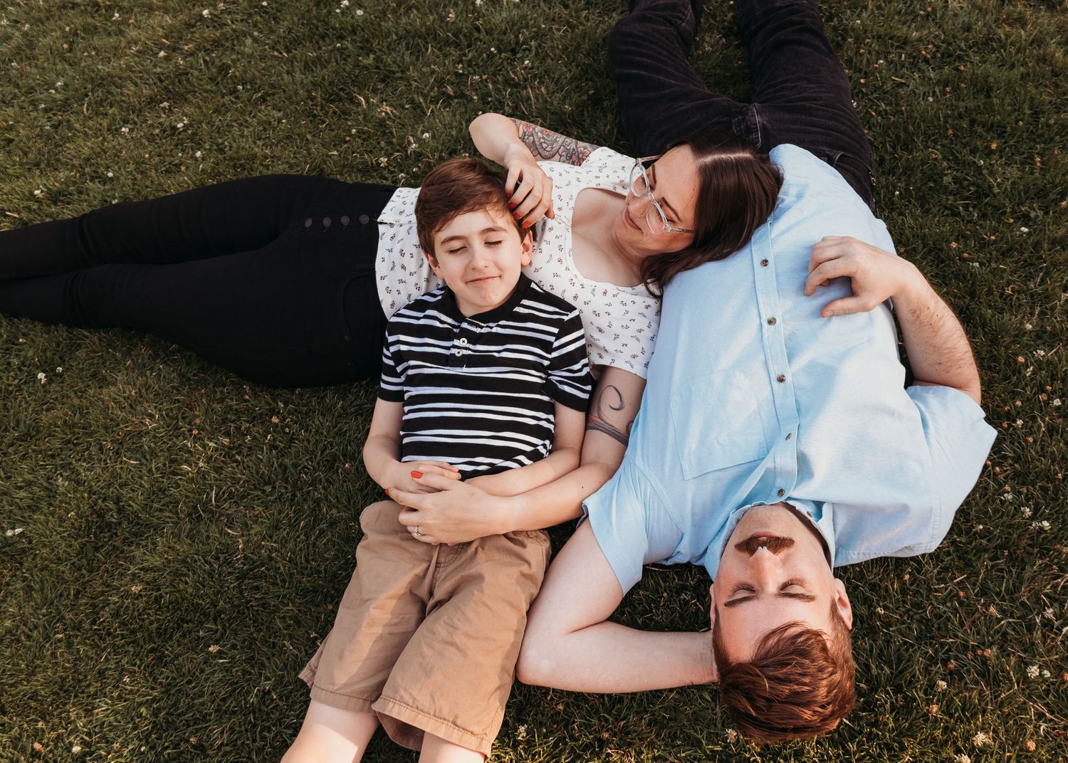 Family members laying on grass enjoying a peaceful moment outdoors.