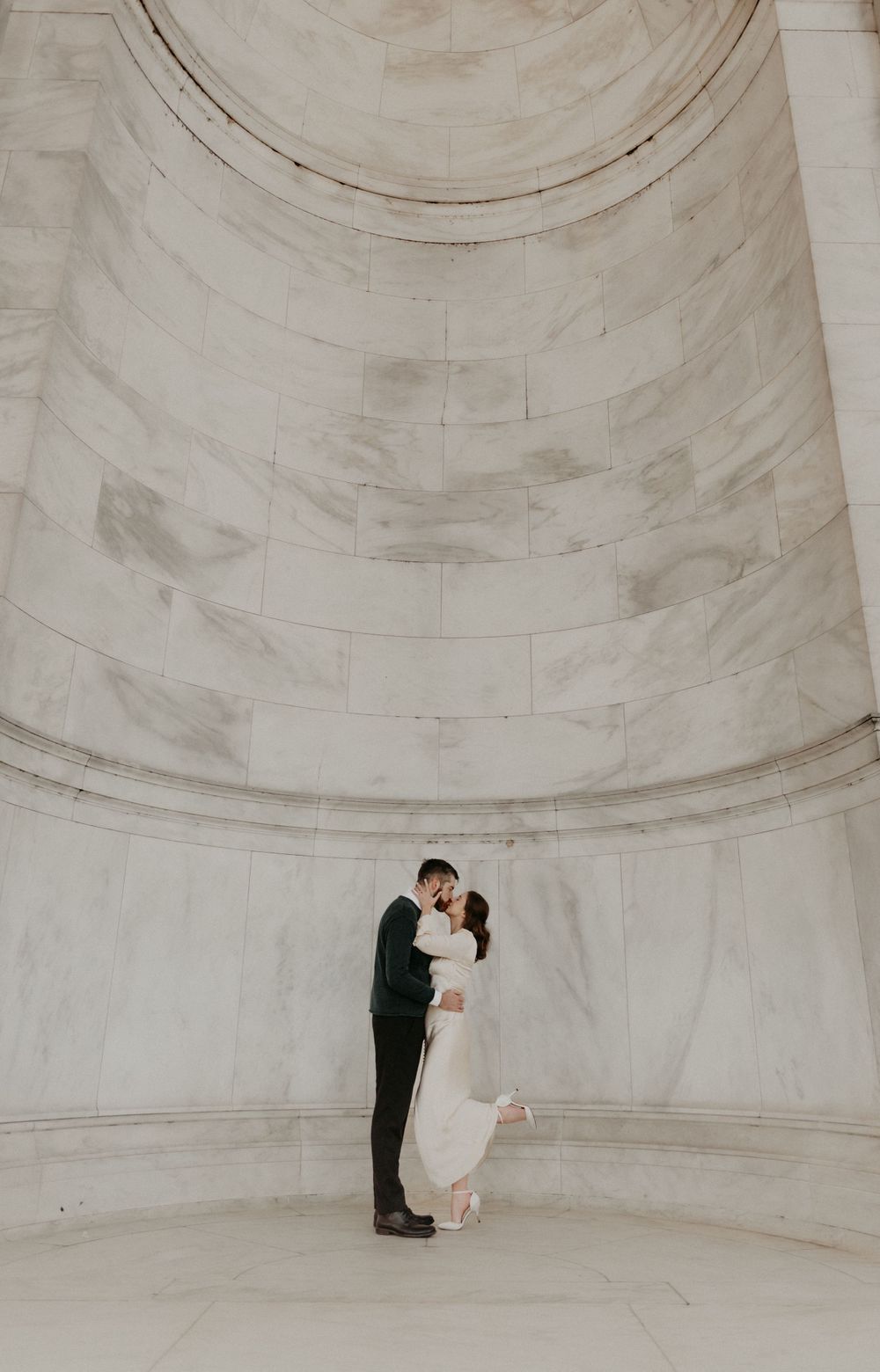 Couple shares intimate moment under grand domed marble architecture.