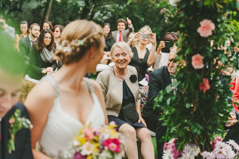 Bride's mother smiles at her daughter during wedding ceremony.