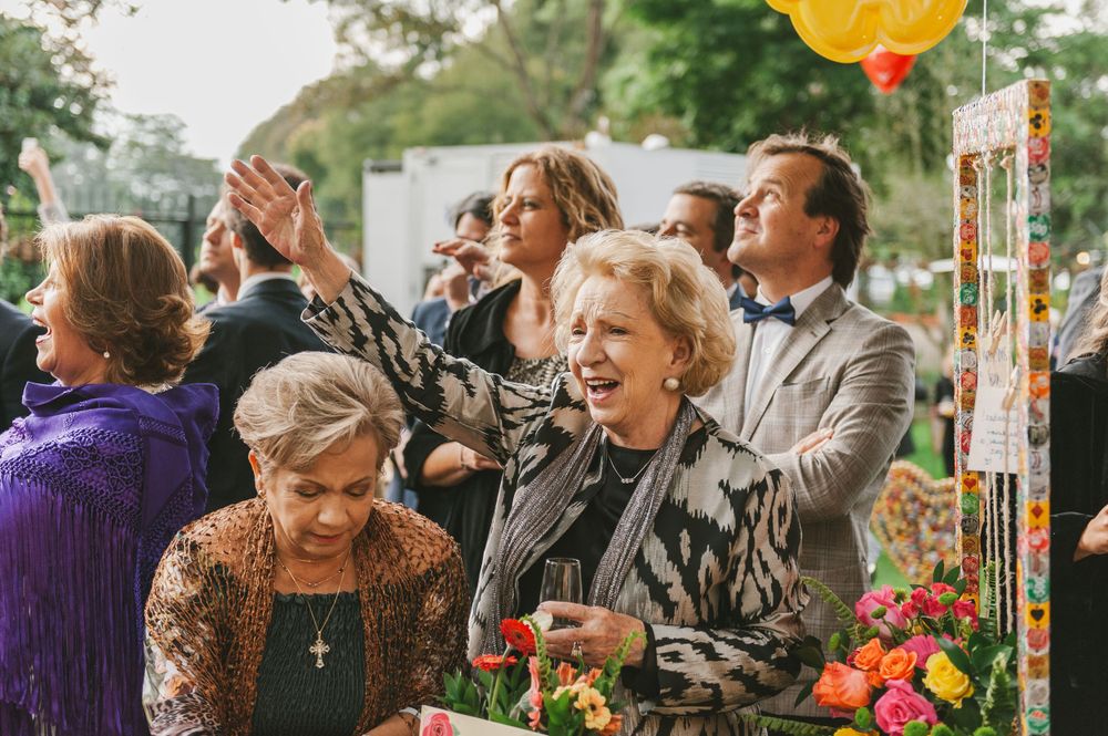 Elderly woman salutes the newlyweds at an outdoor wedding reception.
