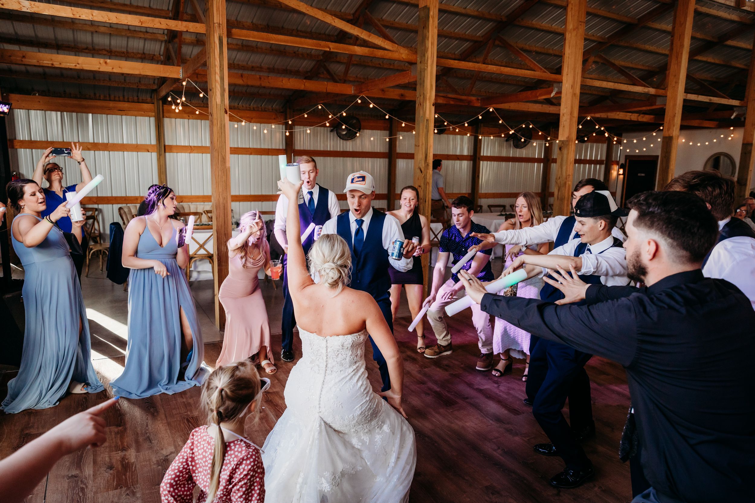 Wedding guests dancing and celebrating on a rustic barn dance floor during a lively wedding reception.