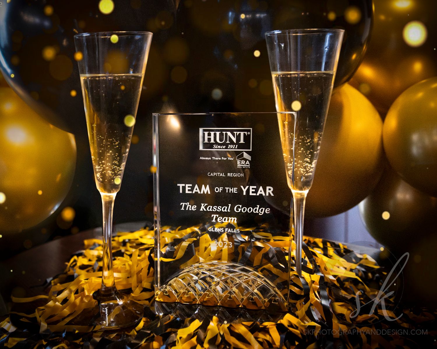 Group of five people posing at an Annual Awards Celebration event with black and gold balloon decor.