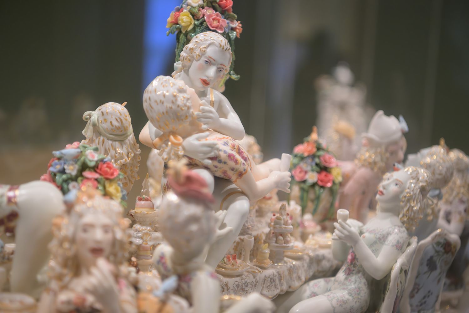 Intricate white porcelain figurines adorned with colorful flowers arranged in an elaborate decorative ceramic sculpture display.