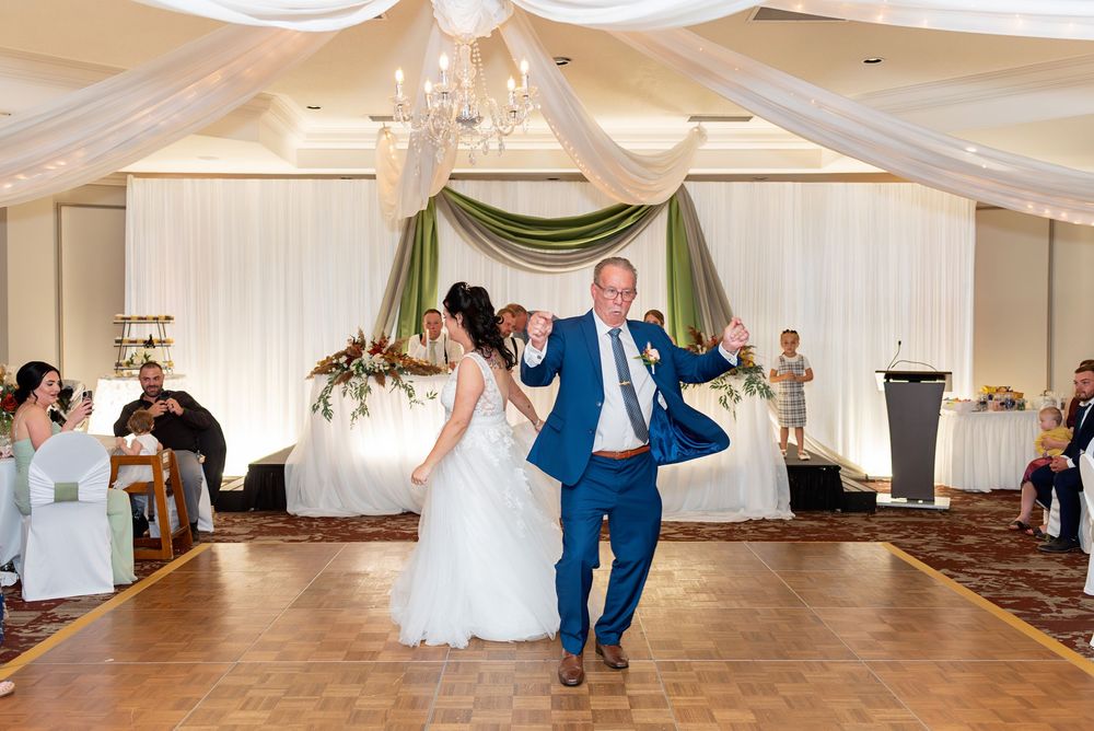 Bride and groom make grand entrance onto dance floor at elegant wedding reception with draped ceiling decor.