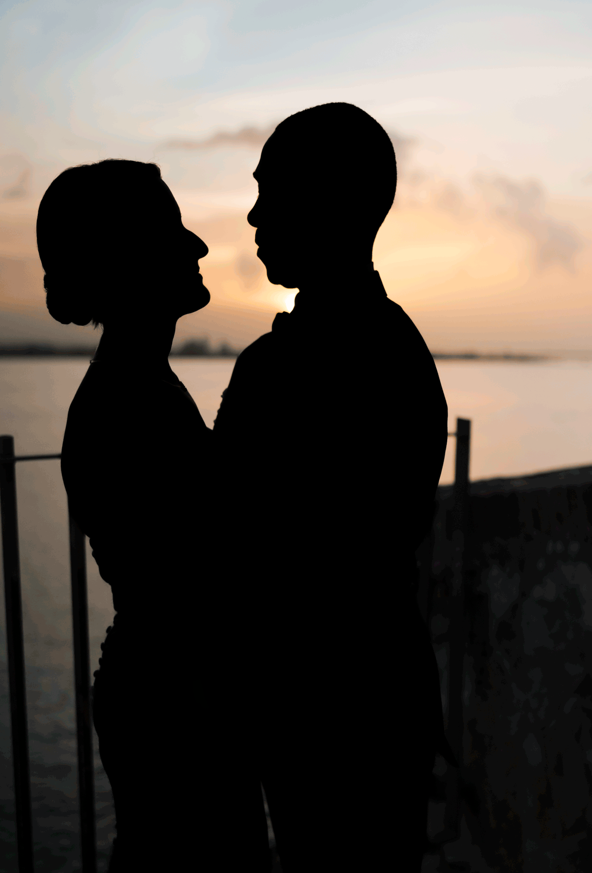 Romantic silhouette of couple kissing at sunset with ocean view