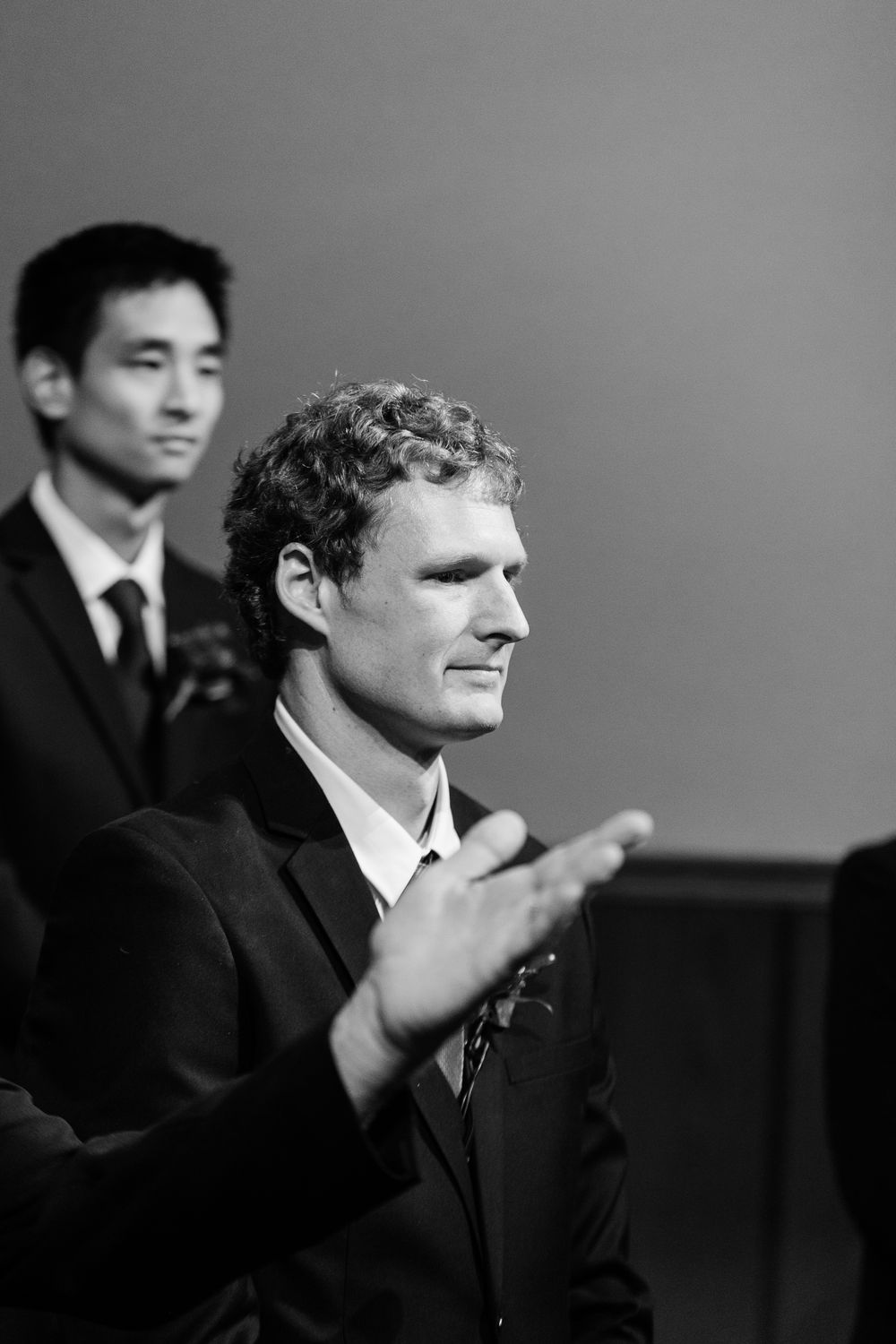 Two men in suits at a formal event, one clapping in black and white photo.