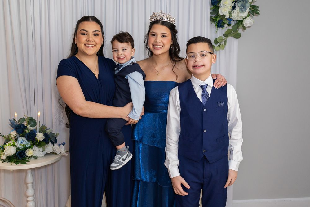 Family portrait featuring four people in navy blue formal attire posing together at an elegant event.