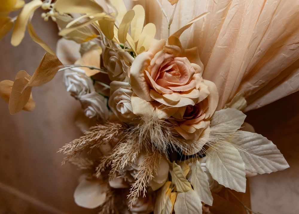 Elegant dried floral arrangement featuring peach roses and golden leaves for a wedding bouquet.