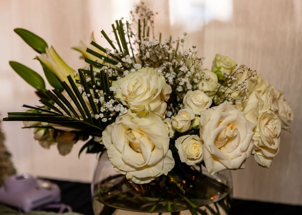 Elegant white roses and baby's breath arranged in a clear glass vase centerpiece.