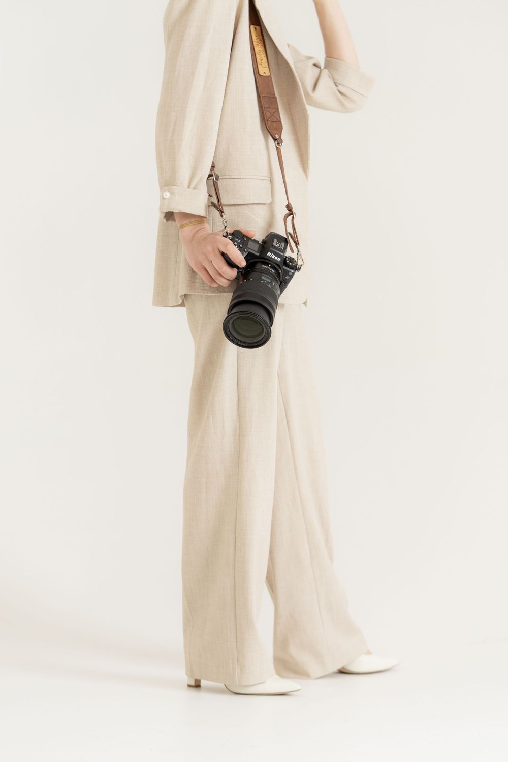 Commercial detail image of a camera and a woman in an ivory suit.