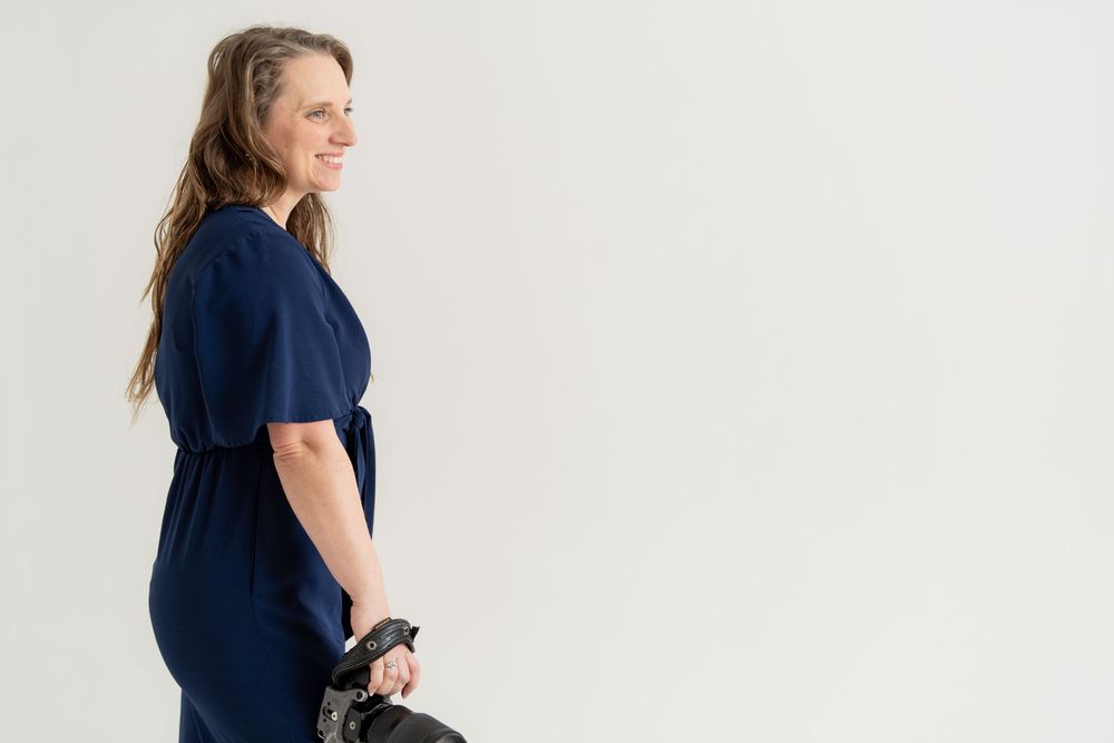 Beautiful woman in a blue suit holding her camera looking off frame.