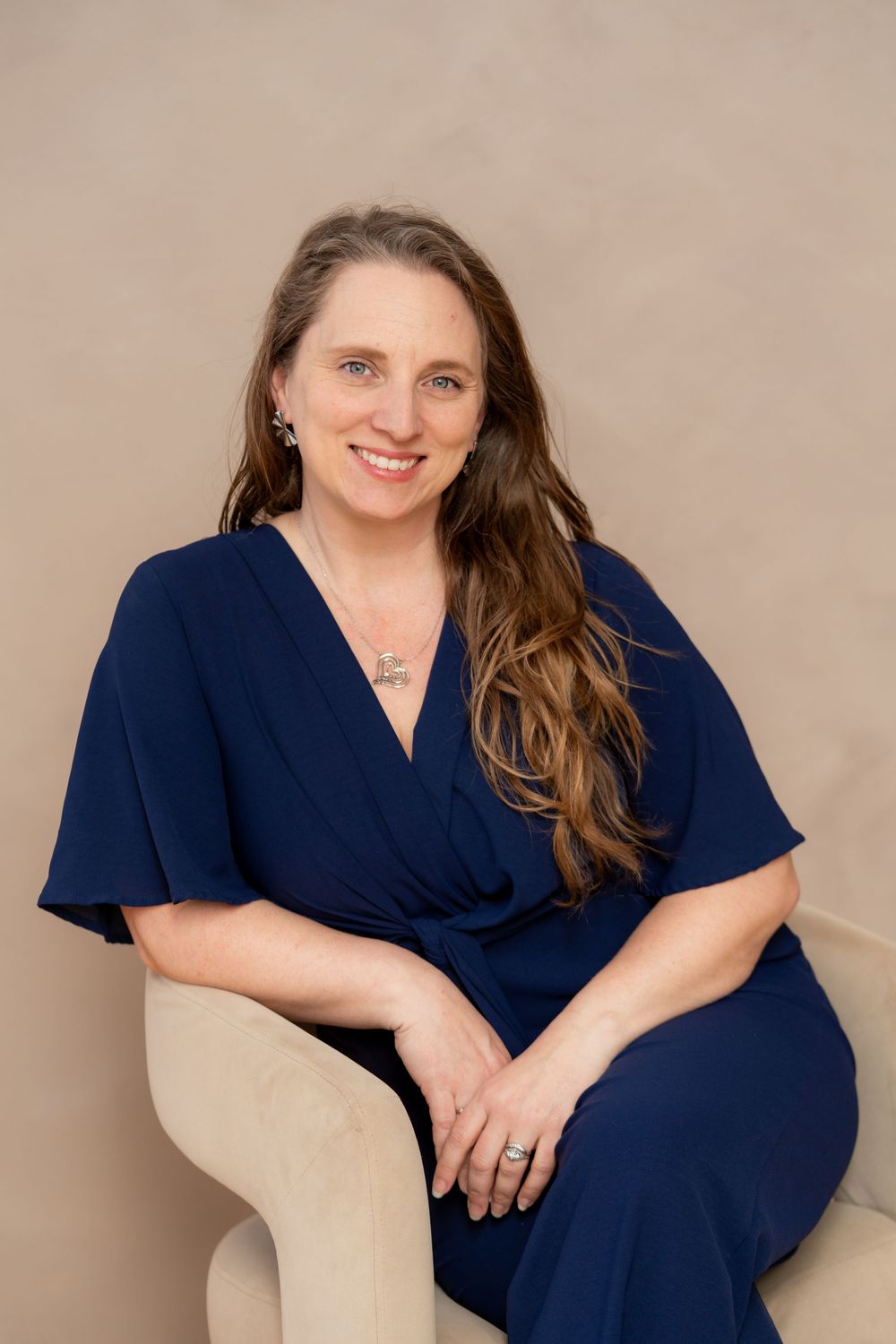 Portrait of a woman sitting in a chair wearing a blue suit in Chelsea MI