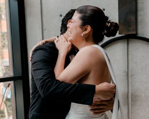 Bride and groom share an emotional embrace, with the groom gently cradling her face during their wedding day.