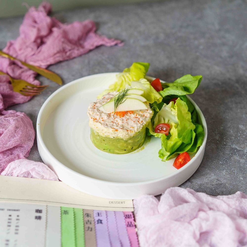 A series of elegant plated dishes with pink and green elements arranged on white plates against a gray background.
