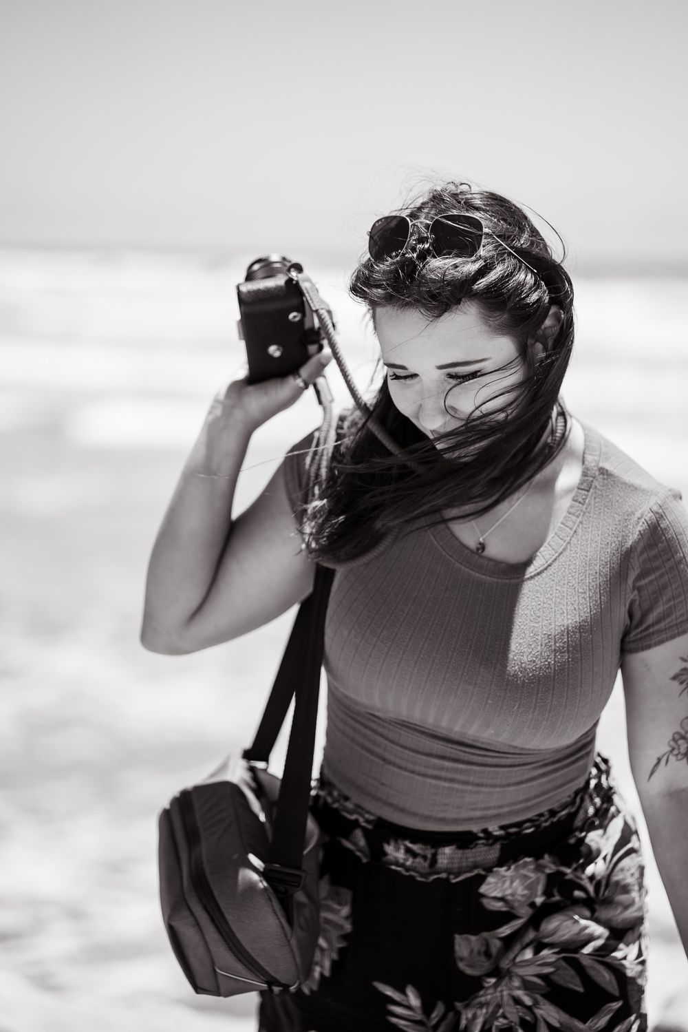 Southern California female beach photographer, looking down and smiling while holding film camera. Oceanside, CA