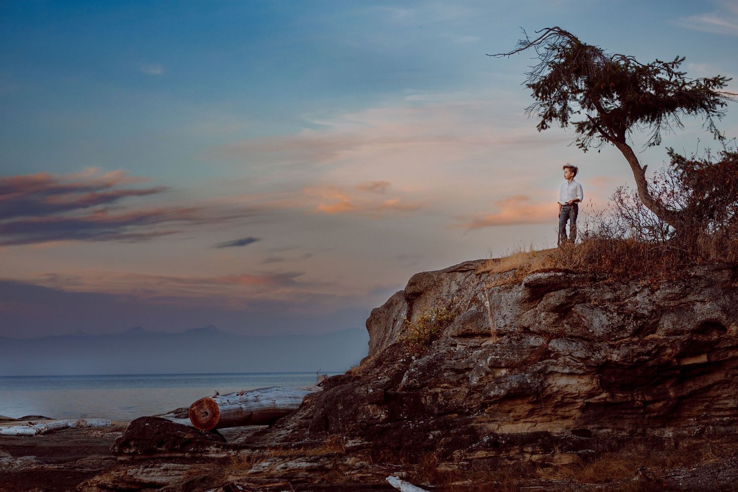 Boy standing on cliff at sunset in Nanoose Bay